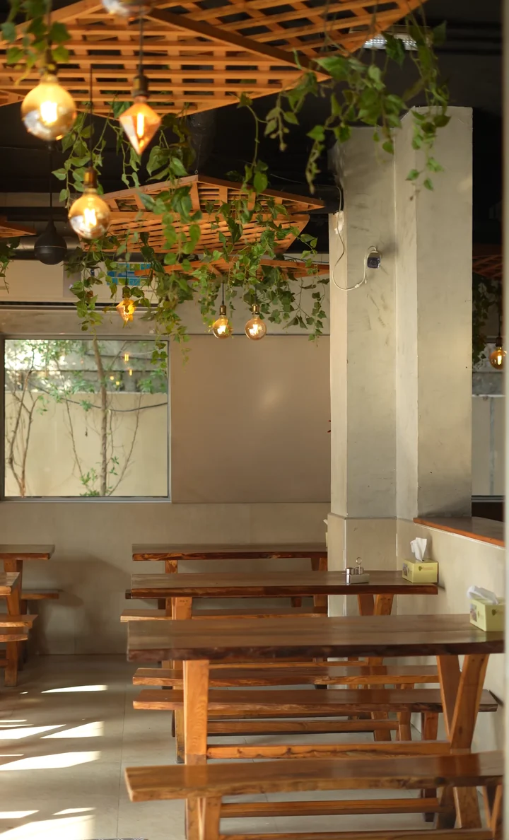 Wooden lattice ceiling with plants and warm lights over the tables at Aaraamam Near Karama Fish Market