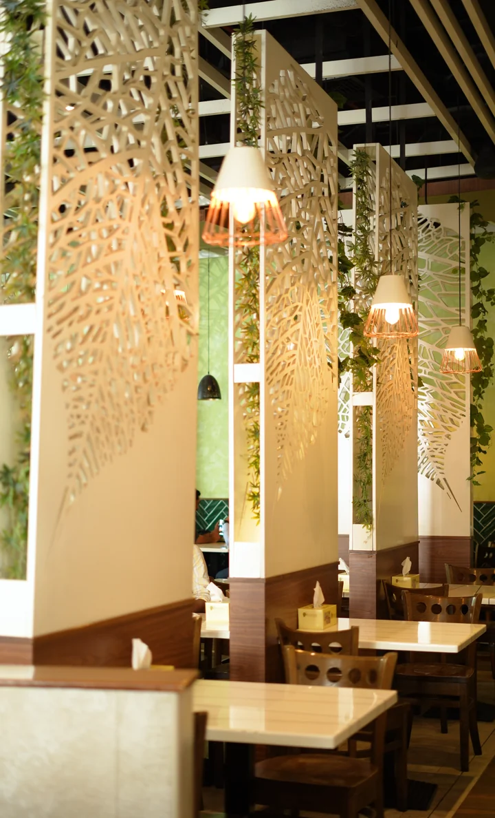 Carved leaf screens and pendant lights in the dining room at Aaraamam Rolla Street, Bur Dubai