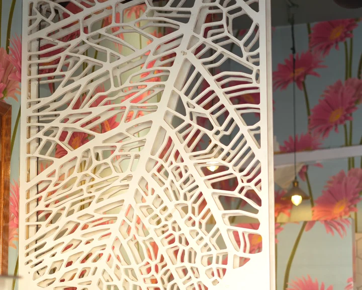 Carved leaf screen against a floral wall at Aaraamam Star, Karama